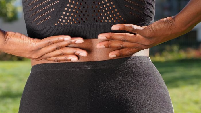 Rear view showing hands resting on the lower back