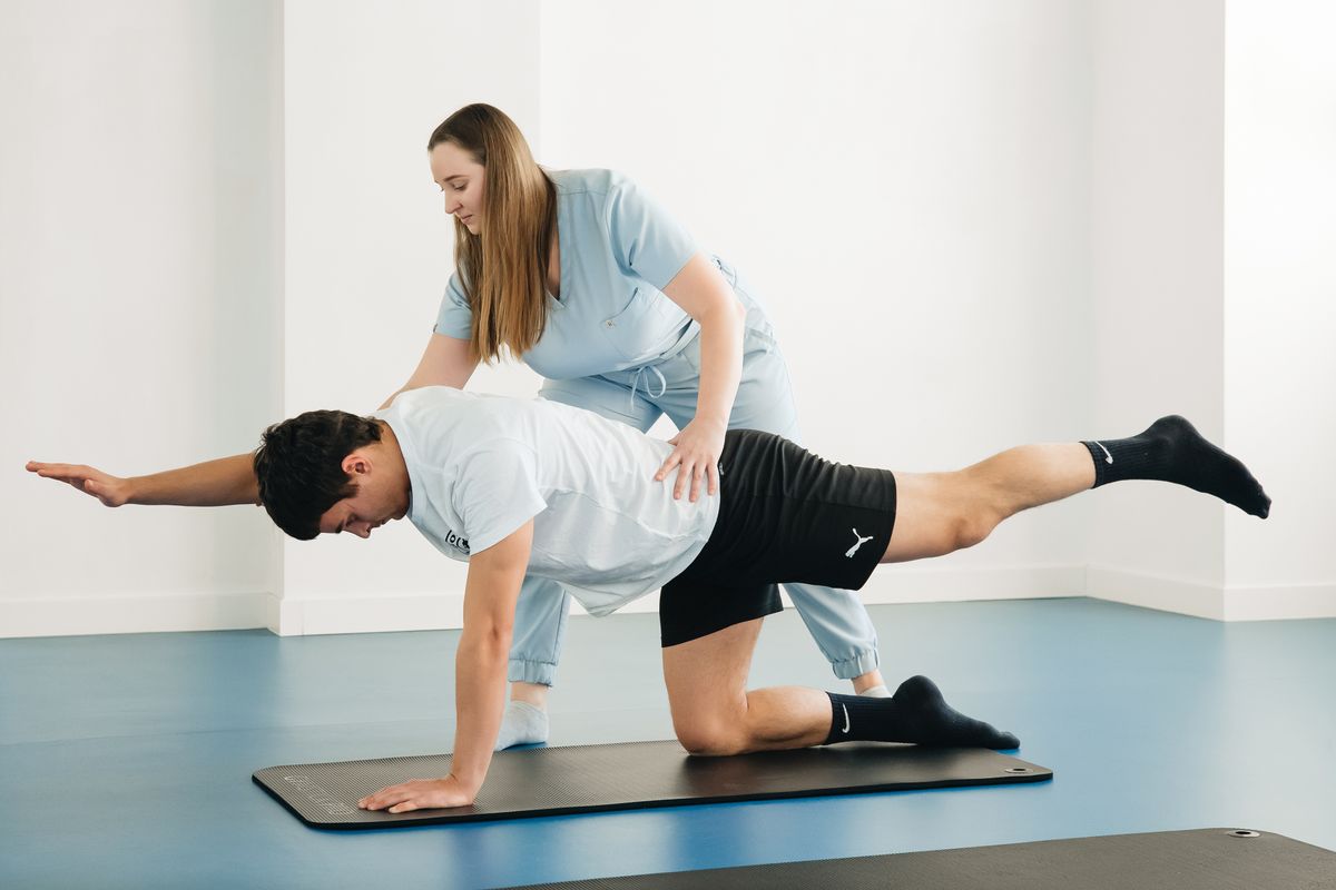 Stock photo of a physiotherapist guiding an adult through a supported movement exercise