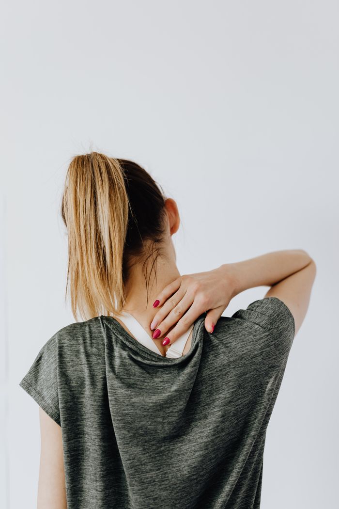 Rear view of a person holding the back of their neck