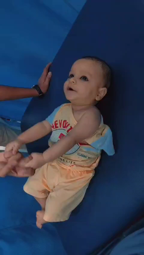 A young child supported in a seated position on a clinic mat