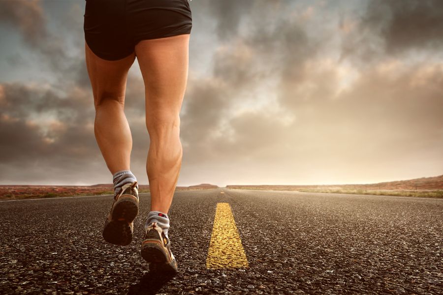 A runner's legs and shoes on an outdoor road